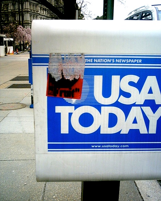 Postal Service sticker painted red, stenciled with a picture of an apple and the word fruit in quotations.